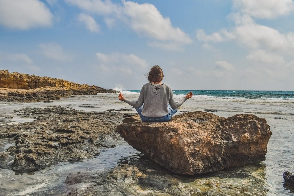 woman by the beach meditating. claire gillies